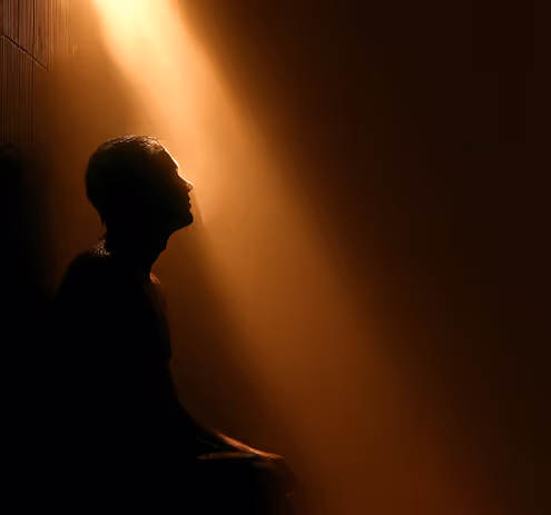 A silhouette of a person sitting in the dark.