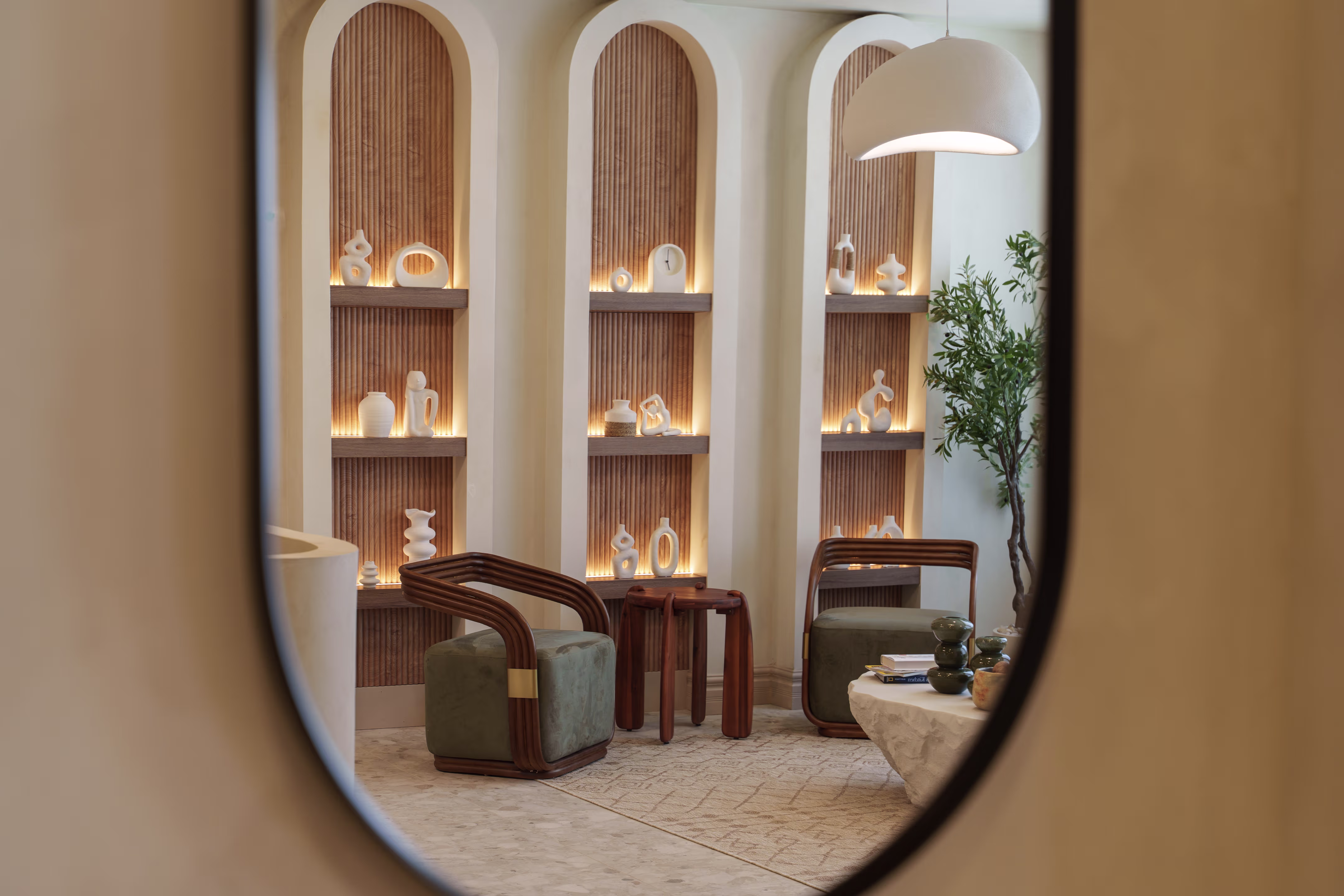 Modern seating area with two wooden chairs, sculptural shelves, a hanging lamp, and a potted plant.