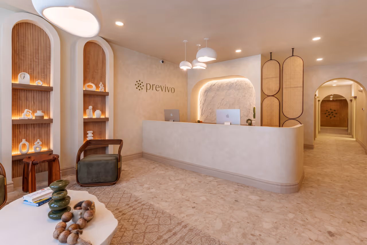 Modern reception area with curved white desk, wood accents, decorative shelves, and soft lighting.