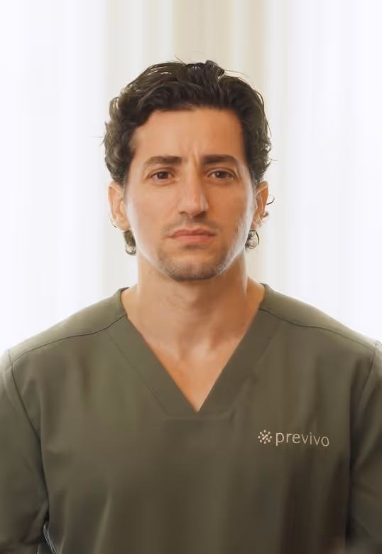 Man with dark curly hair wearing a green Previvo shirt against a light background.