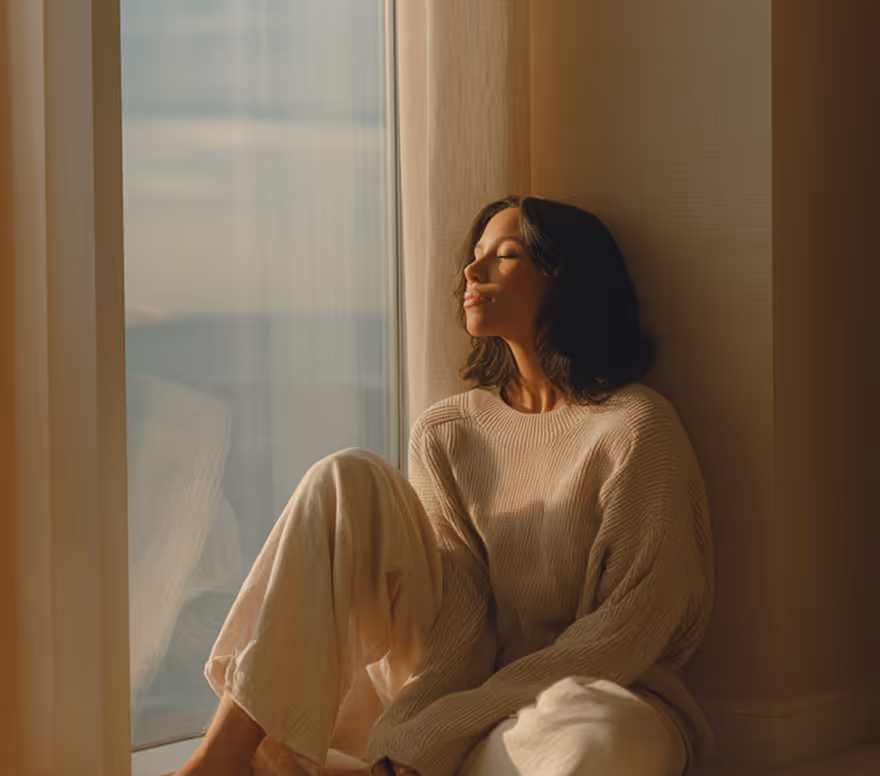Woman seated quietly beside a window